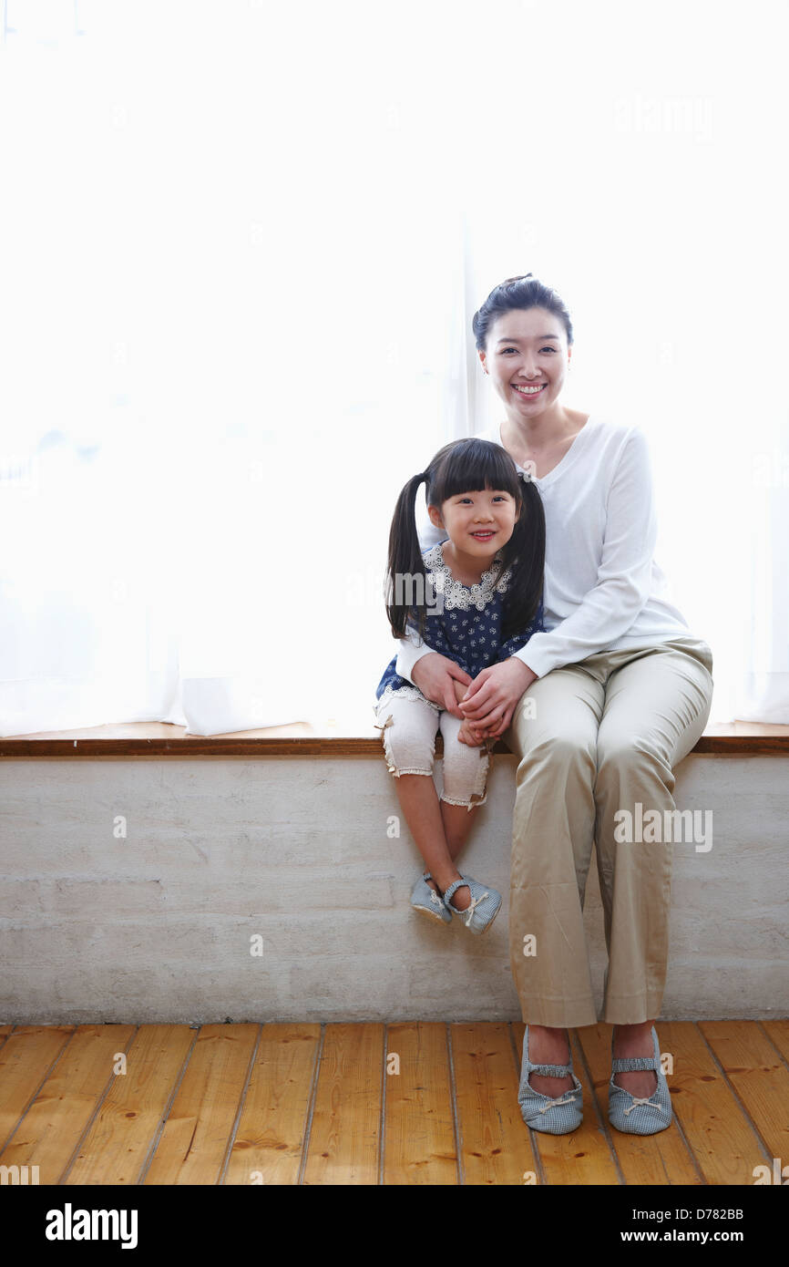 daughter and mother smiling while daughter in mother's arms Stock Photo