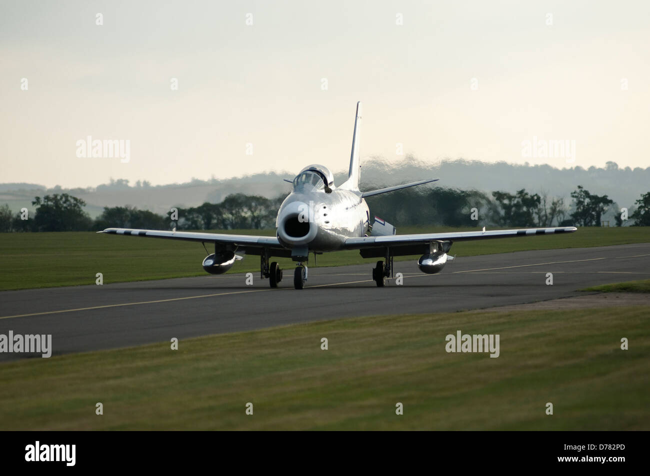 A 1950s USAF F86 jet fighter is seen taxing along an airfield runway. Stock Photo