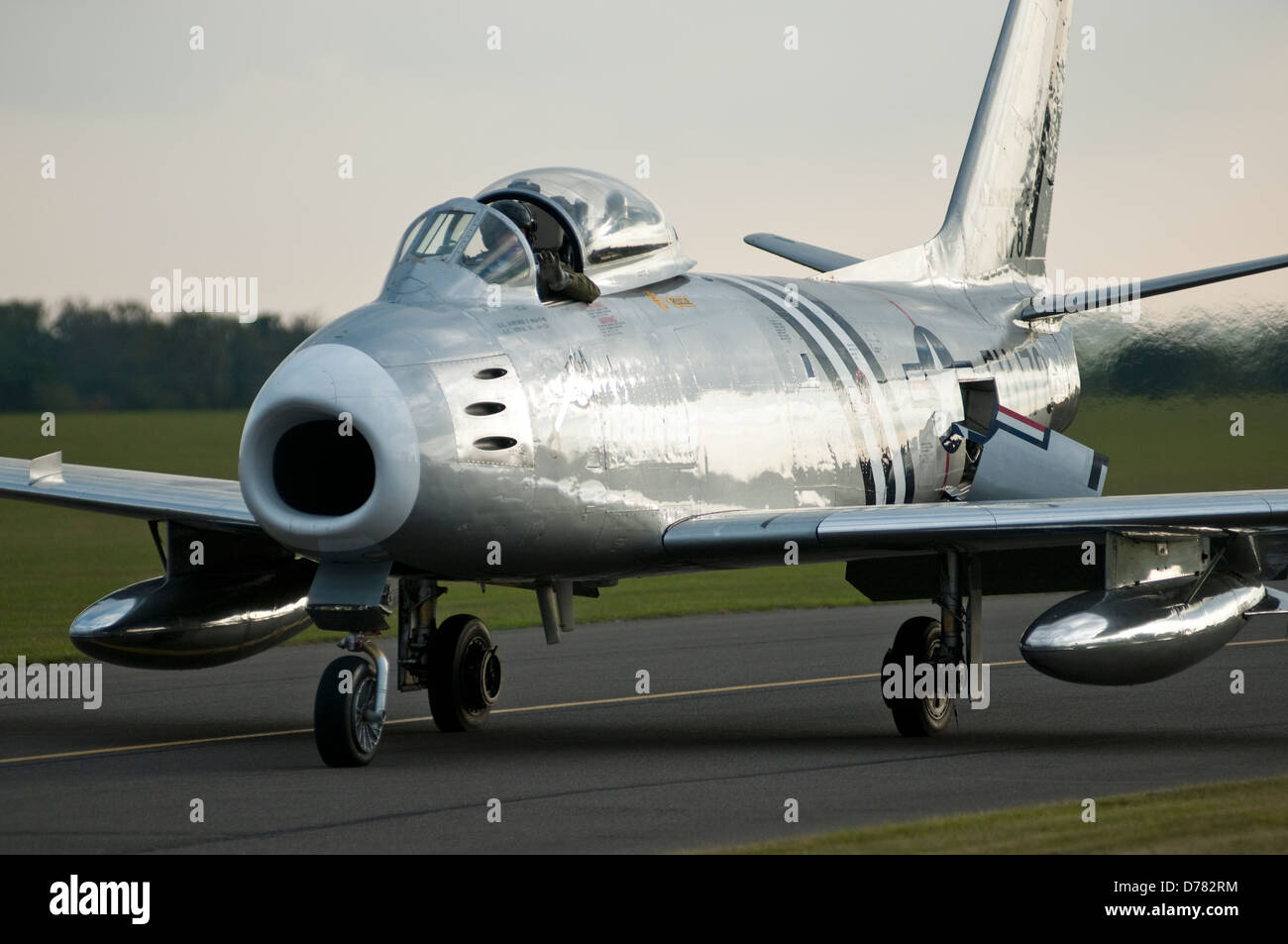 A 1950s USAF F86 jet fighter is seen taxing along an airfield runway. Stock Photo
