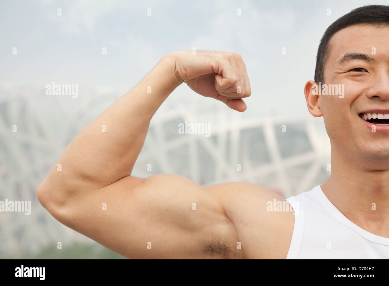 Young man smiling and flexing his bicep Stock Photo - Alamy