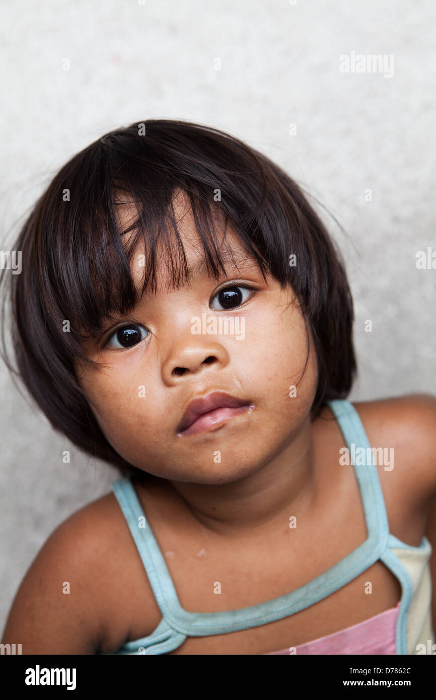 Asian child living in poverty - young Filipino girl against wall Stock Photo