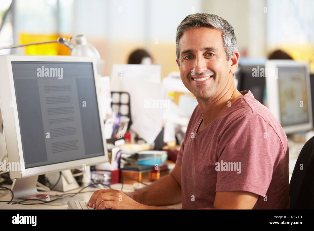 Man Working At Desk In Busy Creative Office Stock Photo