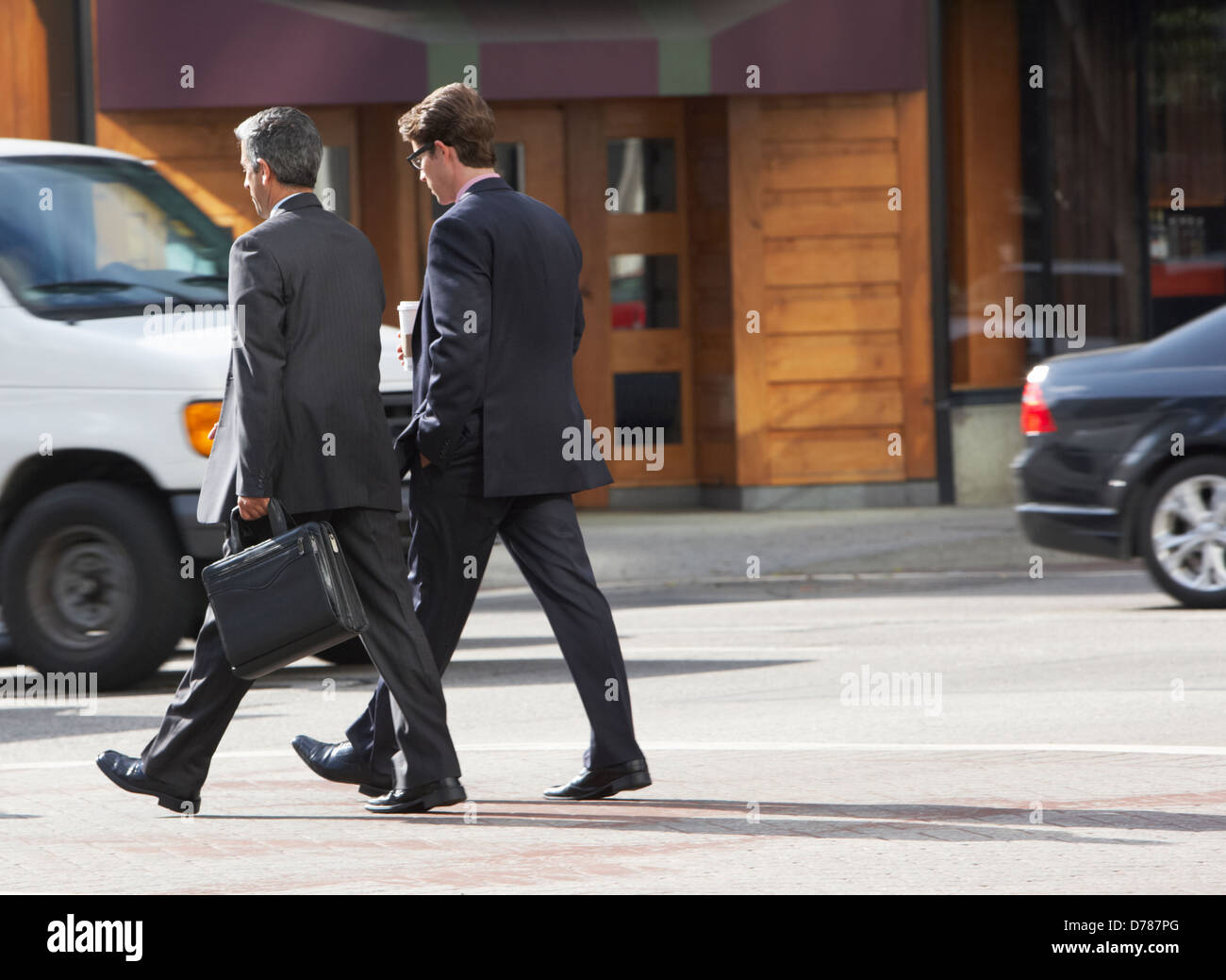 Two Businessman Chatting Whilst Crossing Street Stock Photo