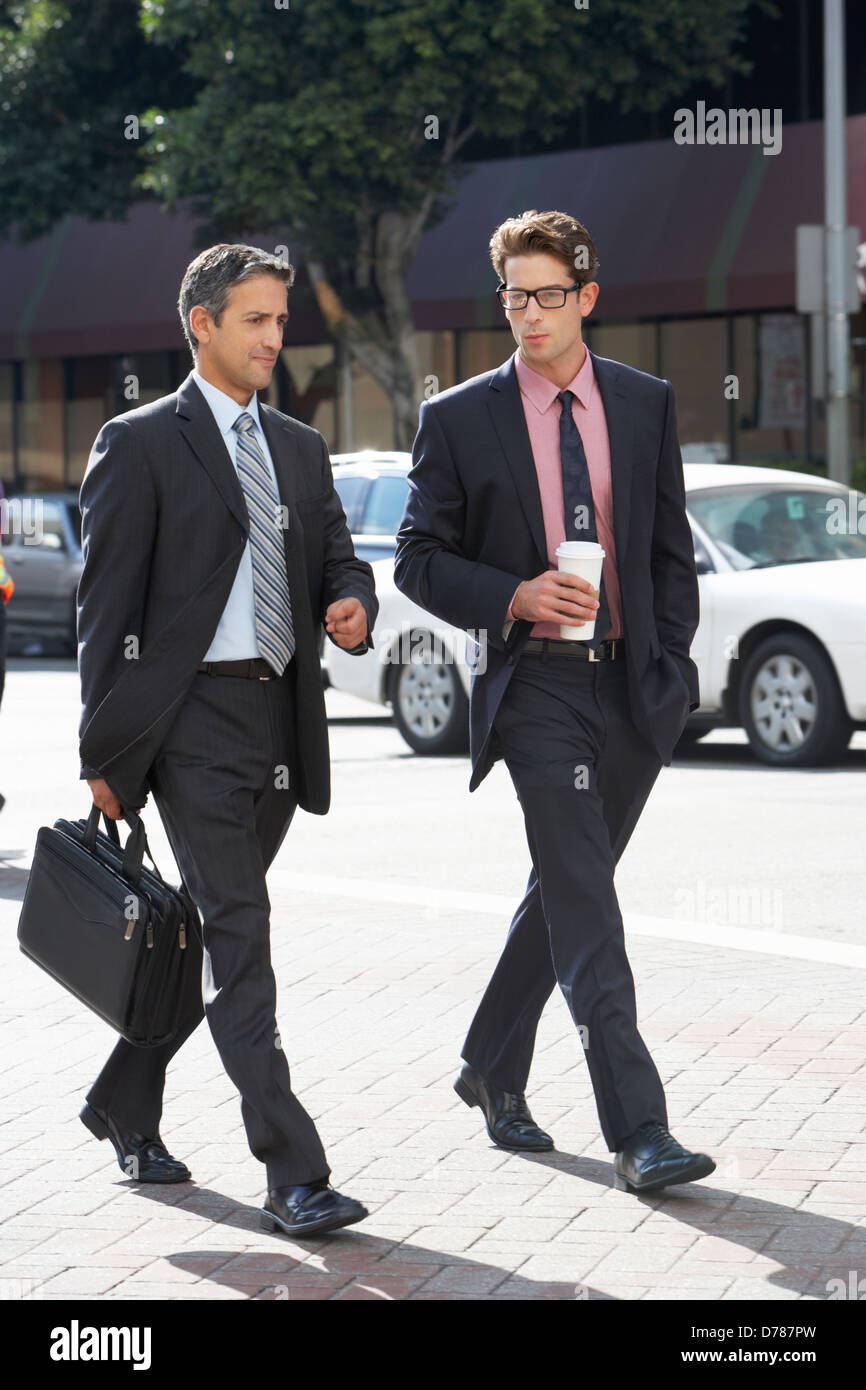 Two Businessman Chatting Whilst Crossing Street Stock Photo