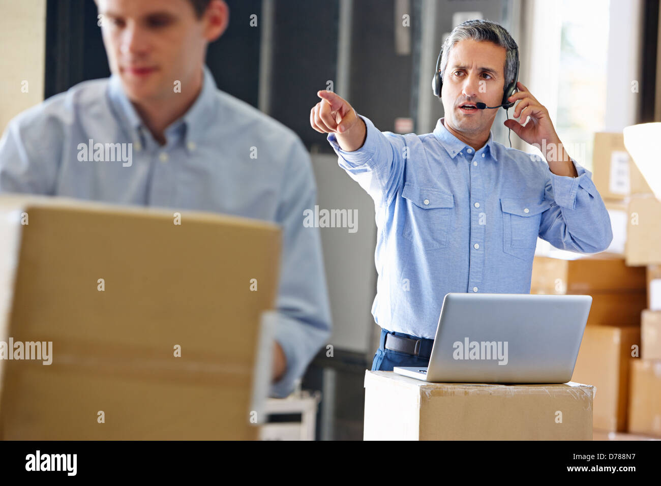 Manager Using Headset In Distribution Warehouse Stock Photo