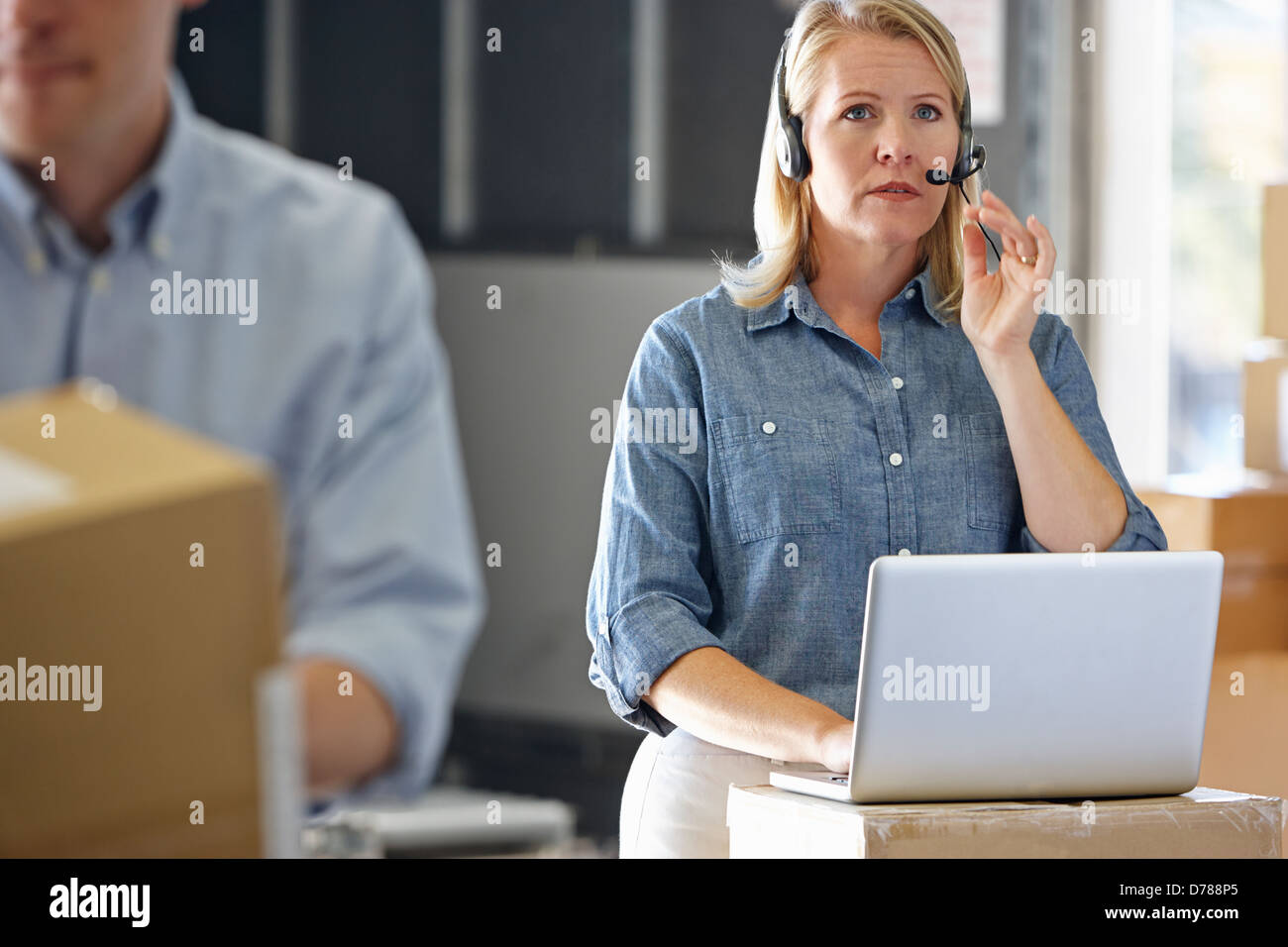 Female Manager Using Headset In Distribution Warehouse Stock Photo