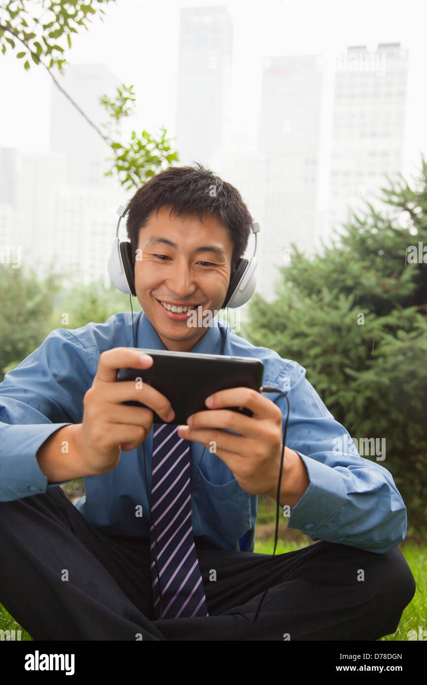 Young businessman listening to music on his MP4 player Stock Photo