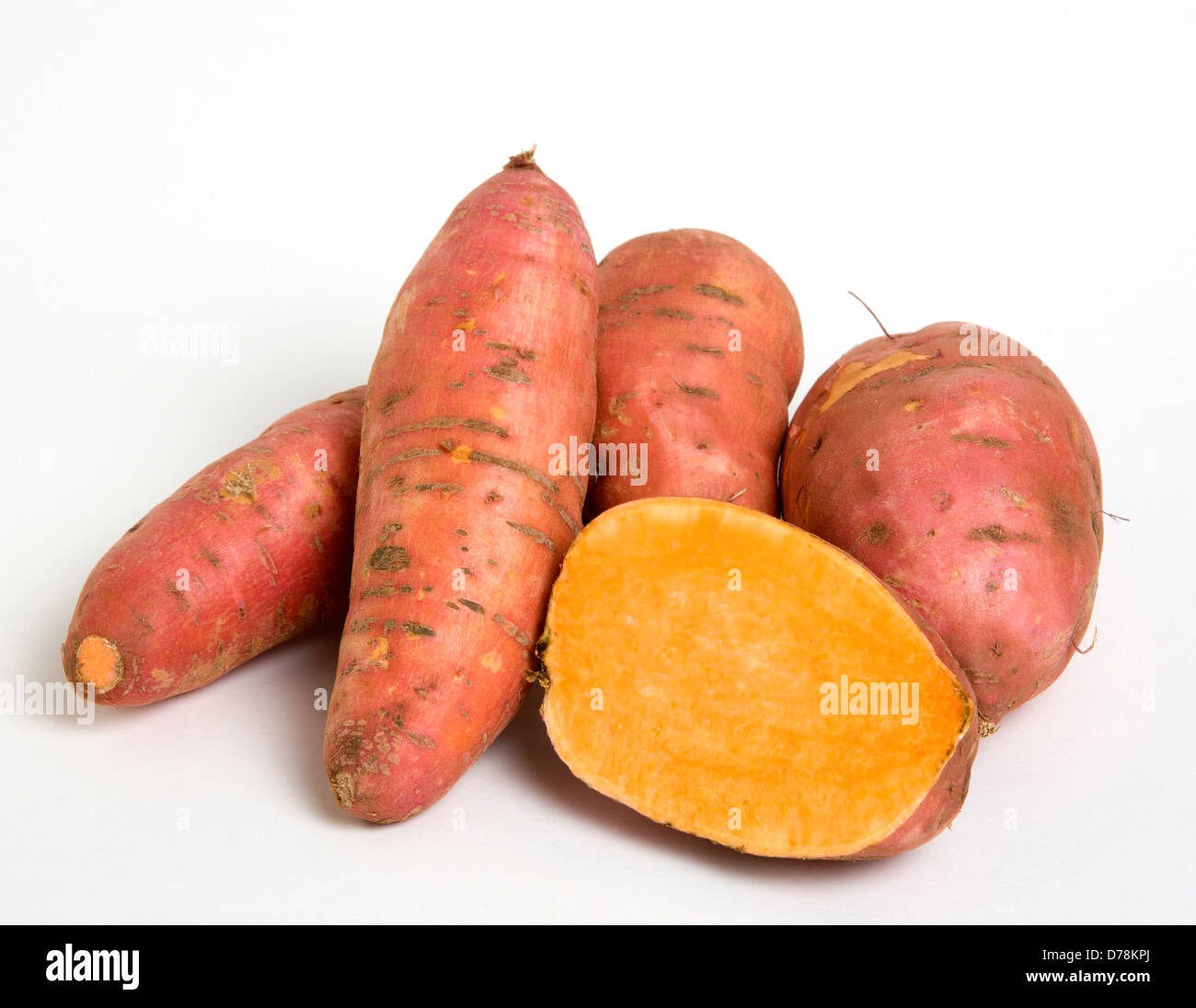 Group shot of Sweet potato, Ipomoea batatas on a white background with one potato cut in half to show the orange interior. Stock Photo