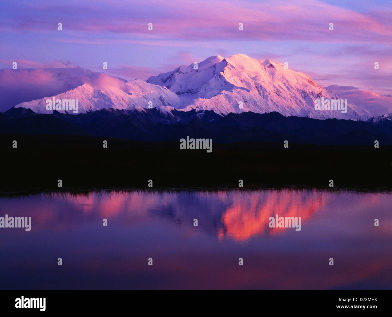 Denali Mount McKinely highest peak in North America 20,320 feet basking in warm light sunset reflected in pond Denali National Stock Photo