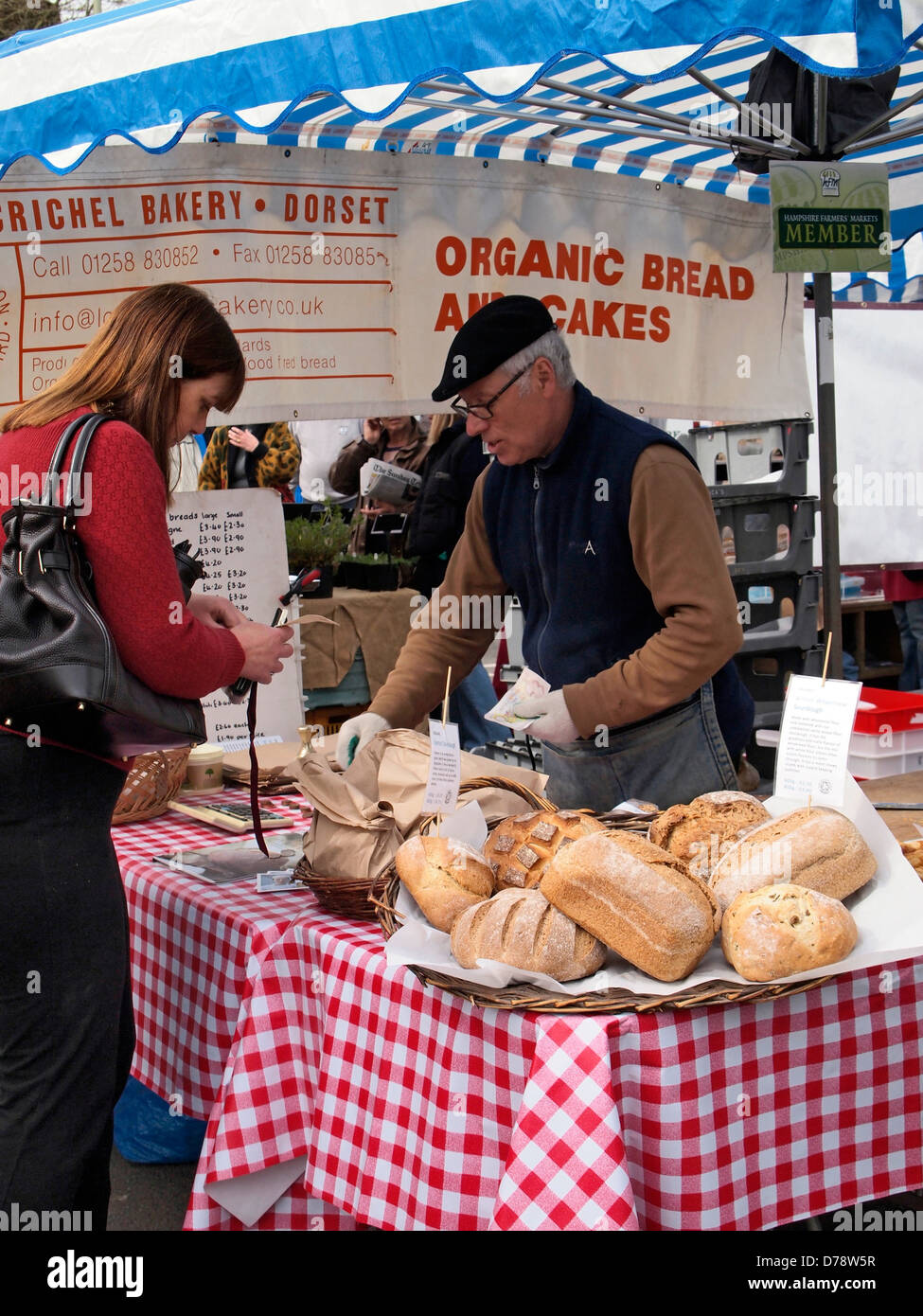 Woman buying organic bread from a stall at Winchester Farmer's Market, Hampshire, England. Stock Photo