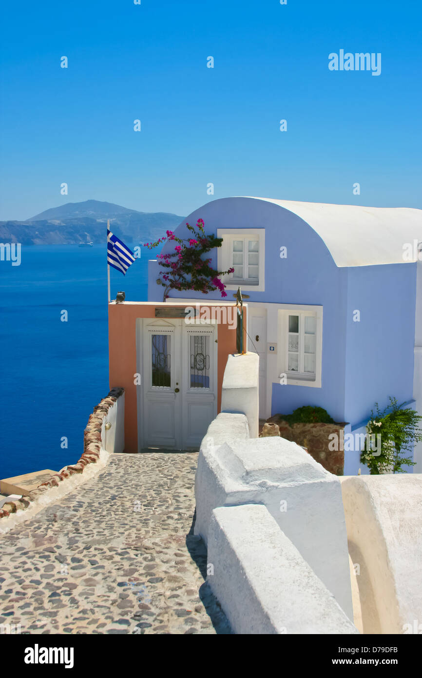 Beautiful house with greece national flag on the street in Santorini, Oia. Aegean sea in a background, Greece Stock Photo