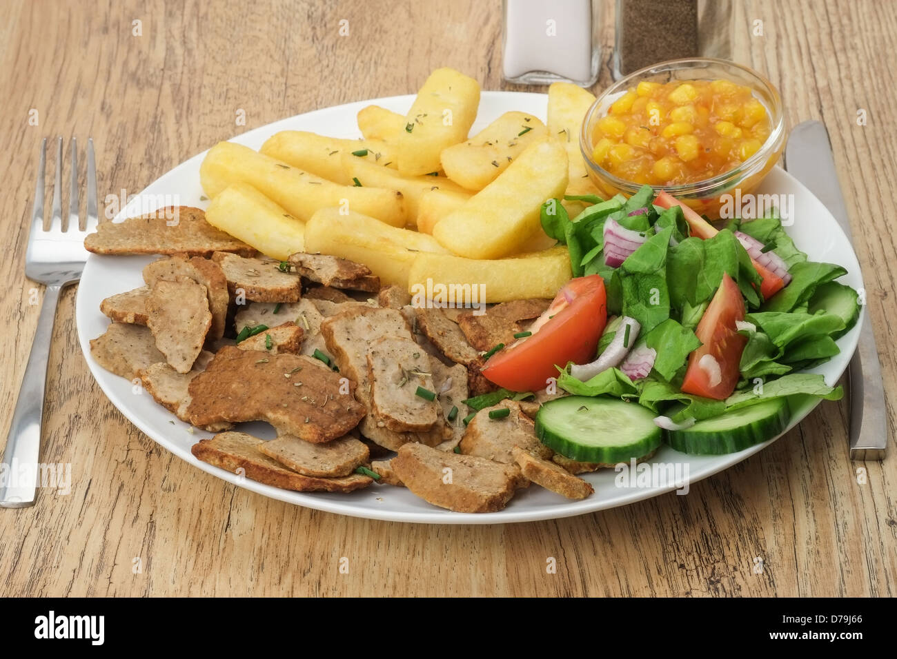 A dinner plate of slices of beef kebab gyros or shawarma meat with fries and salad Stock Photo