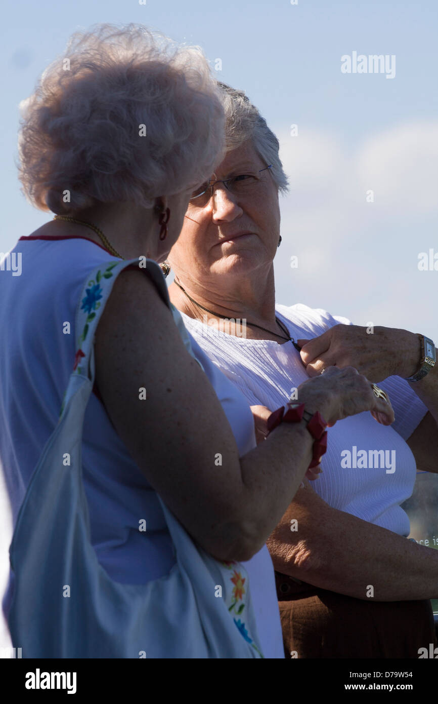 Two elderly women having a serious conversation with their backs to the sun. Stock Photo