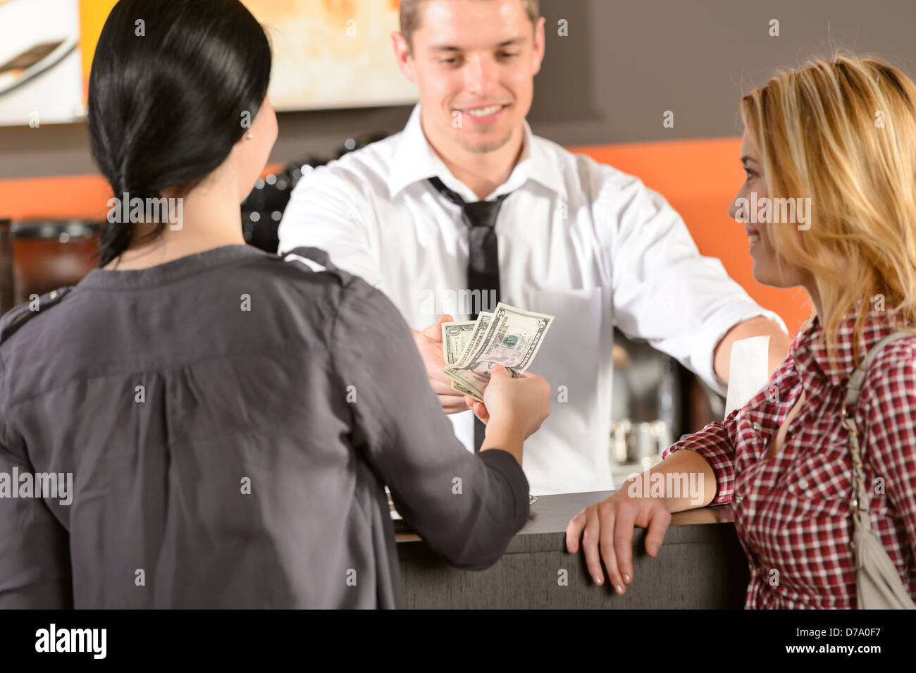 Female customers paying by cash dollar in bar to bartender Stock Photo