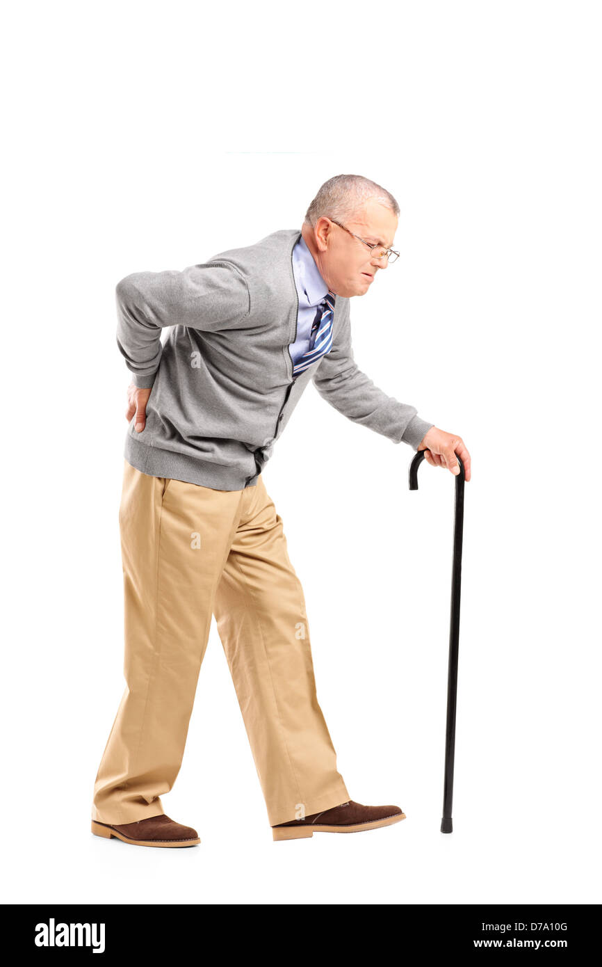 Full length portrait of a senior gentleman walking with cane and suffering from back pain isolated on white background Stock Photo