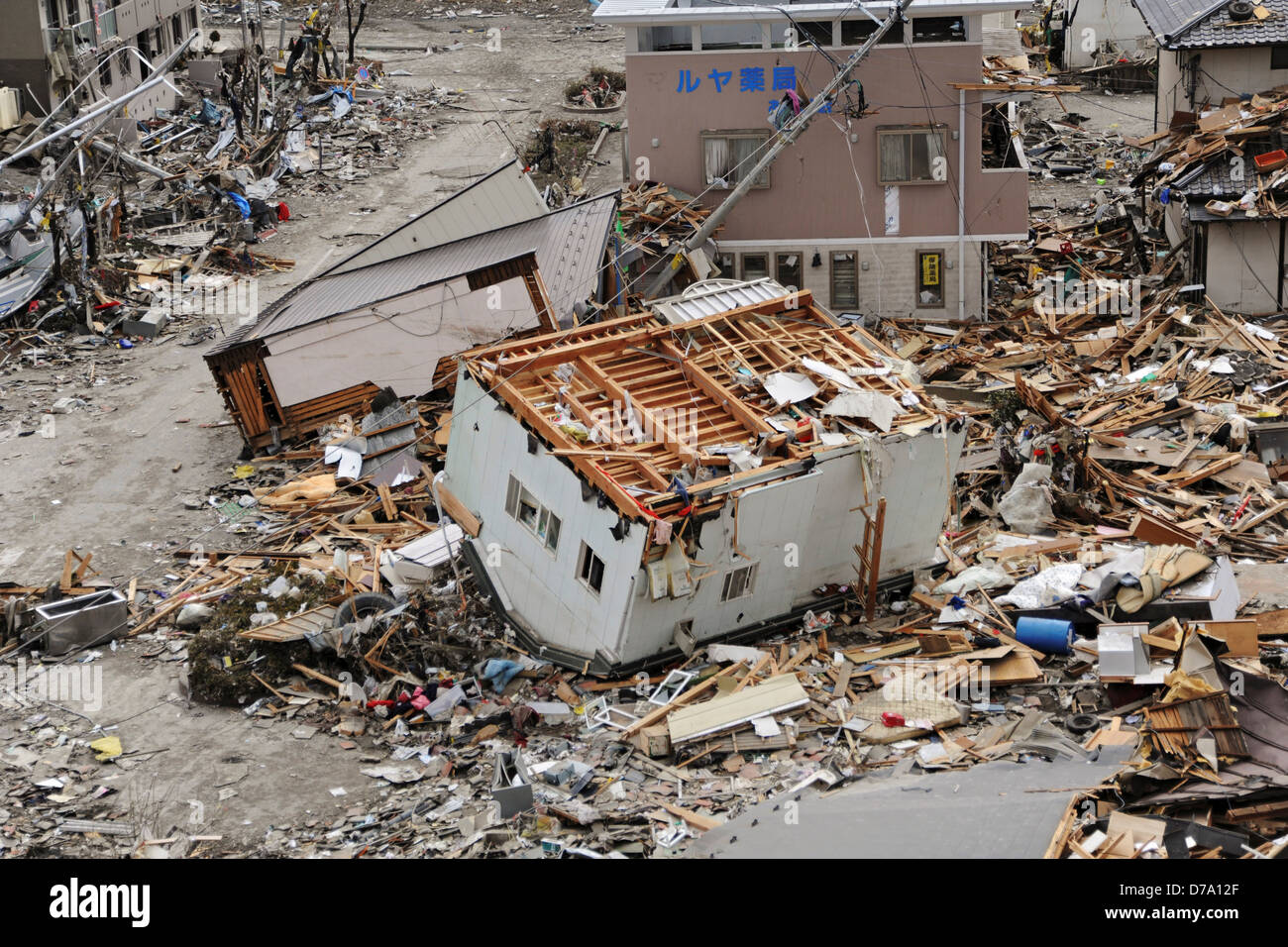 Upended House Among Debris Following Earthquake Tsunami Stock Photo