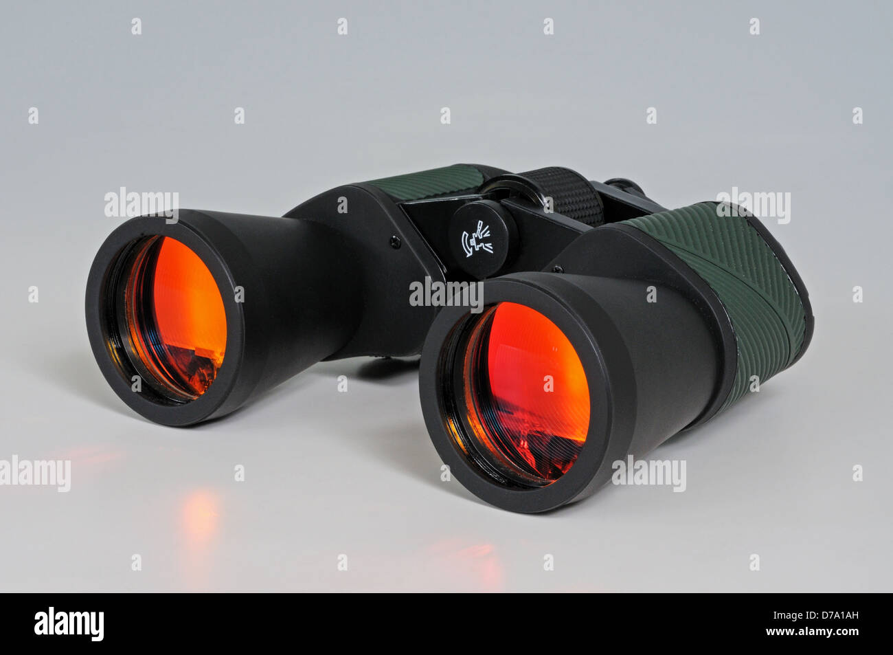 Binoculars with orange antiglare coated lenses against a grey
