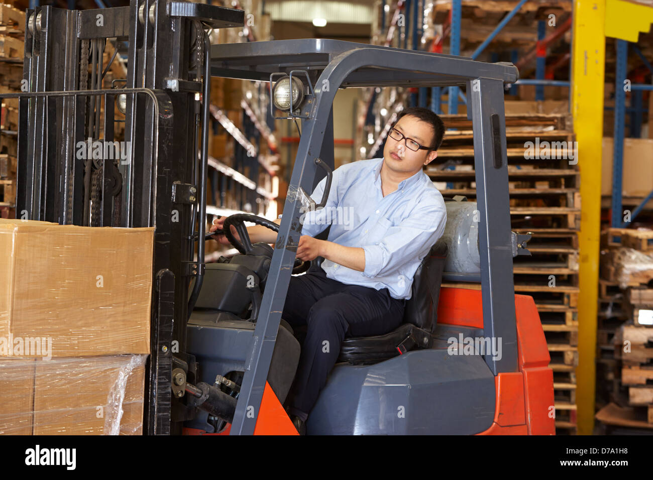 Man Driving Fork Lift Truck In Warehouse Stock Photo