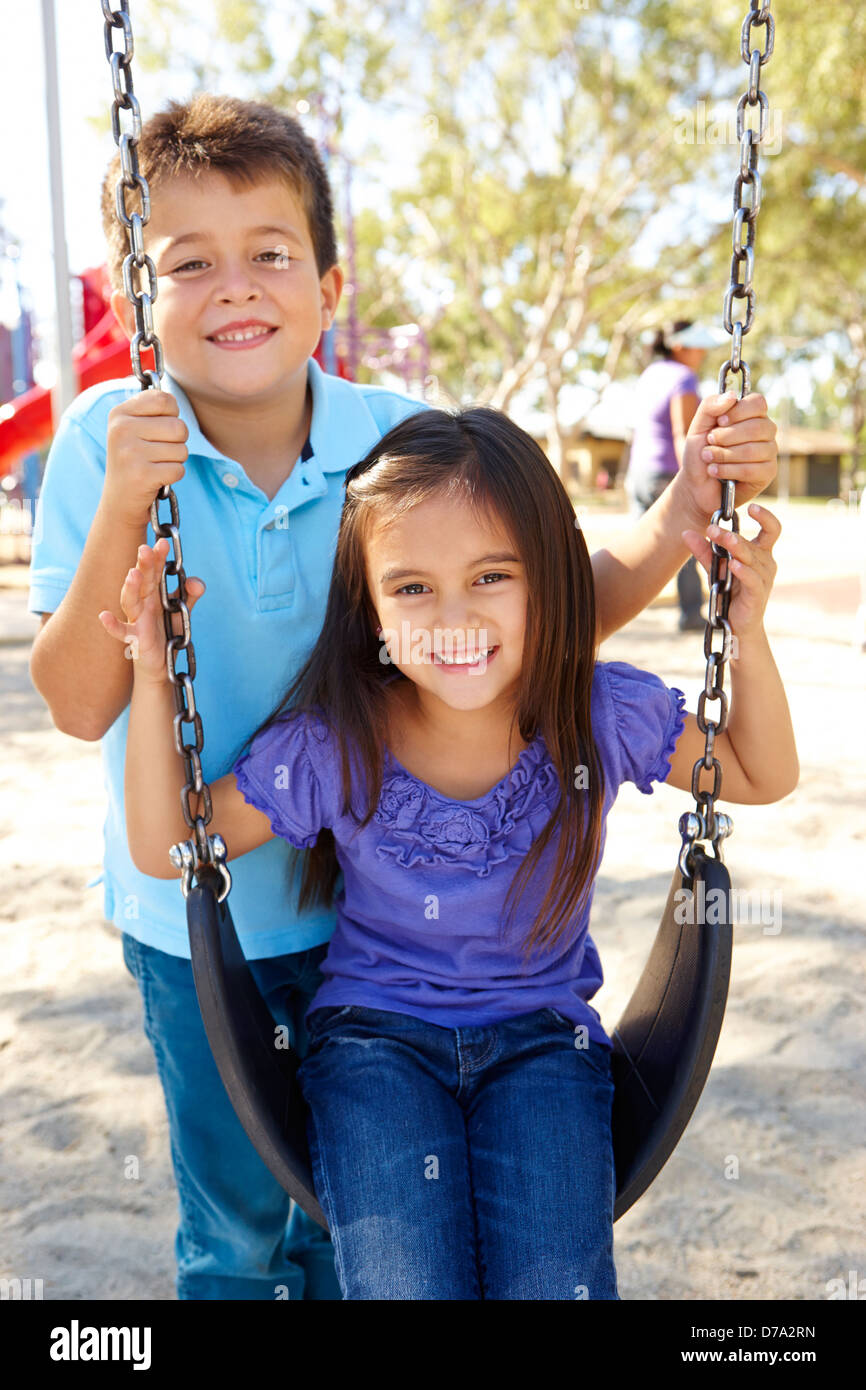 Boy And Girl Playing On Swing In Park Stock Photo