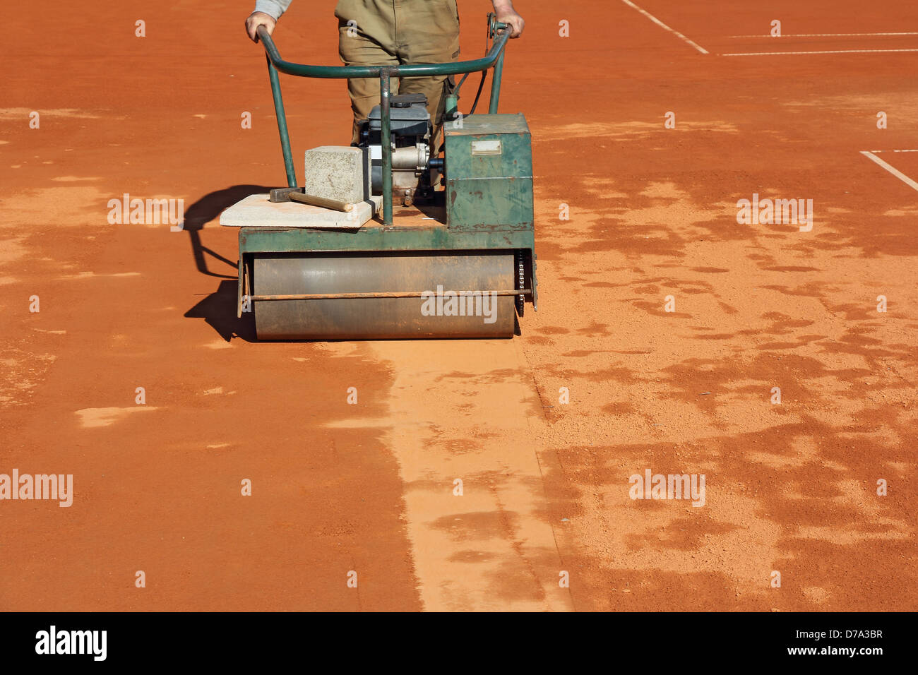 Worker with roller editing clay tennis court Stock Photo