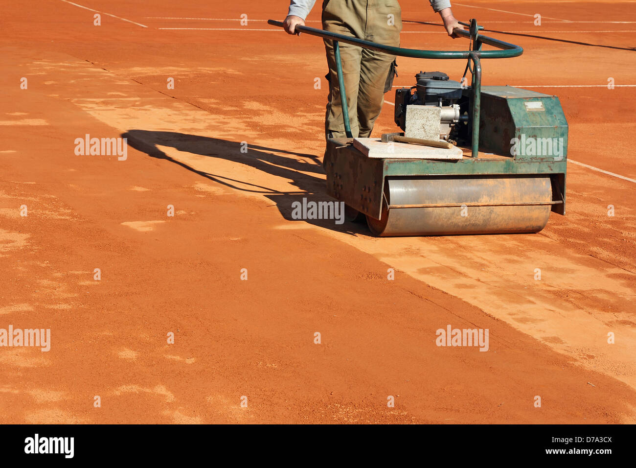 Worker with roller editing clay tennis court Stock Photo