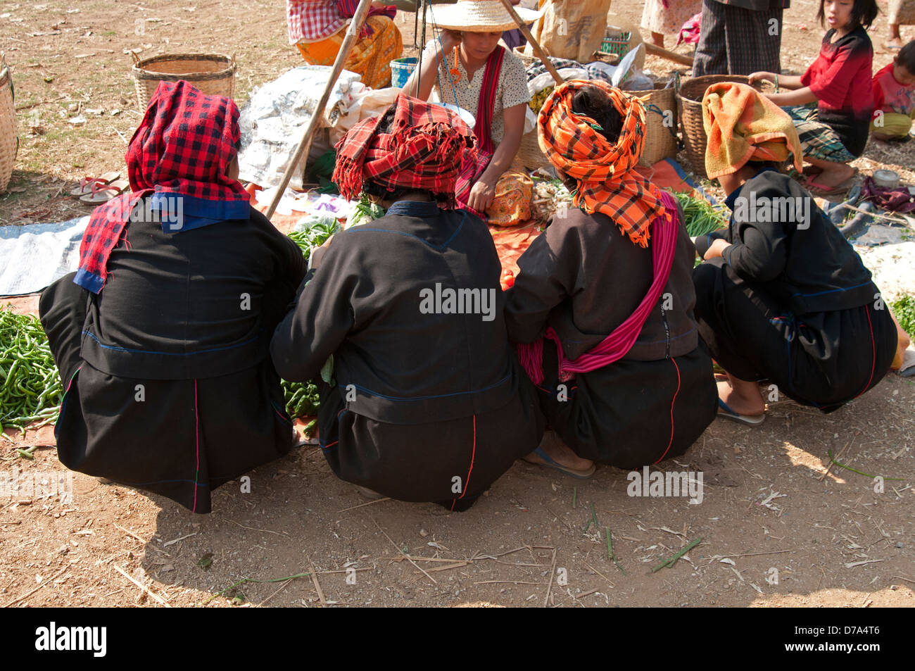 Back view of four Pa-O tribal women squat at a market stall Inthein village Inle lake Myanmar (Burma) Stock Photo