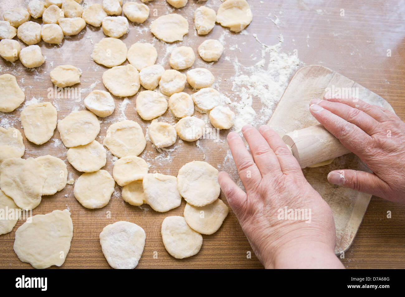 Grandma's hands roll out the dough on wooden table Stock Photo
