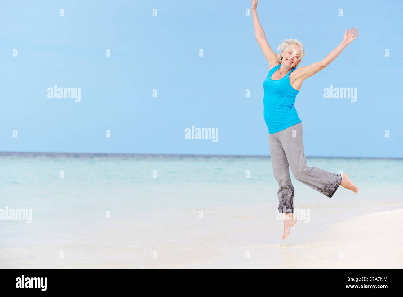 Senior Woman Jumping On Beautiful Beach Stock Photo