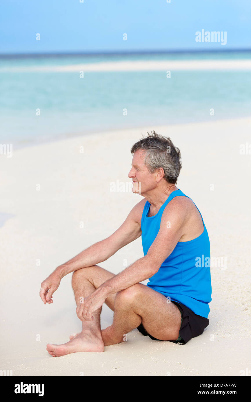 Senior Man In Sports Clothing Relaxing On Beautiful Beach Stock Photo
