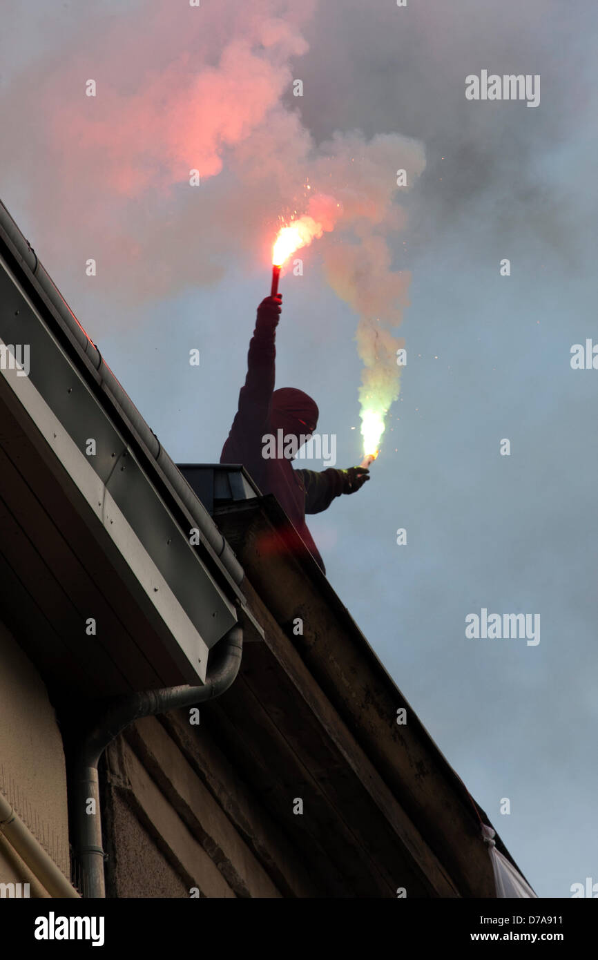 Berlin, Germany. 2nd May 2013. A masked man fires flares on a rooftop as demonstrators pass during labour day demonstrations in Berlin, Germany. Credit:  Rey T. Byhre / Alamy Live News Stock Photo