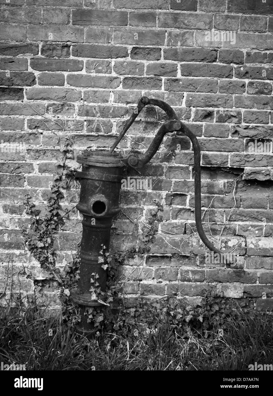 Old water pump against a brick wall. Stock Photo