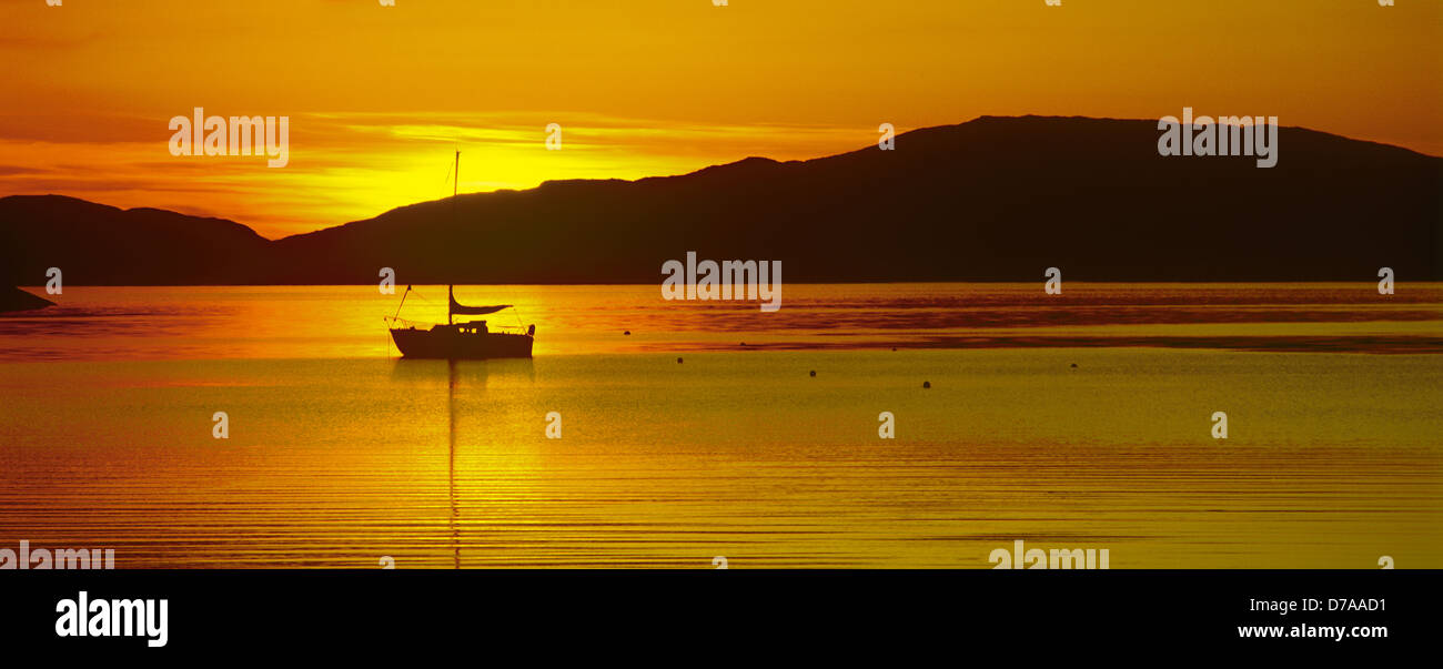 Single sail boat  at sunset, Loch Crinan, Argyll and Bute, Highlands Scotland UK Stock Photo