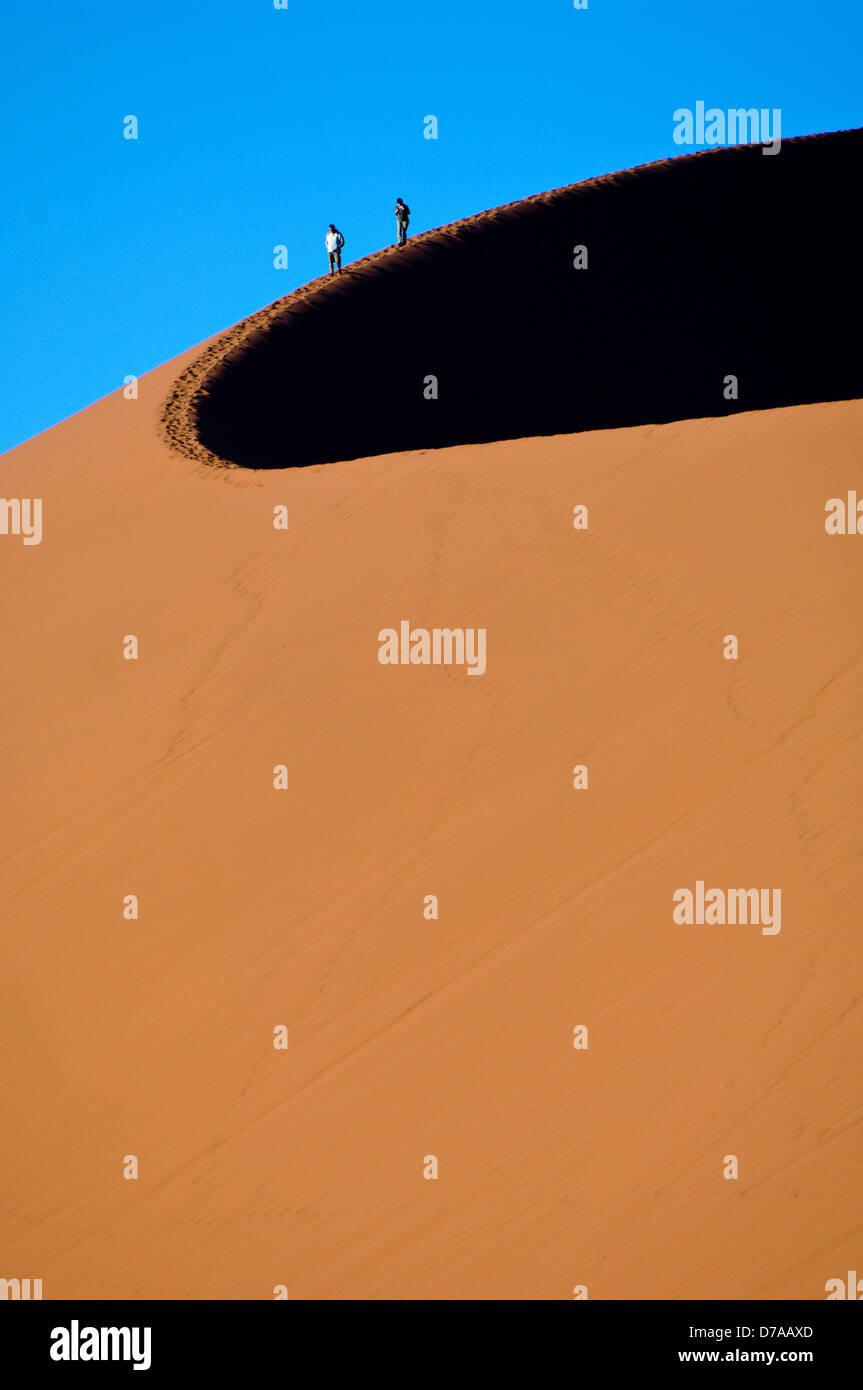 Tourists climbing giant sand dunes Dune 45 at Sossusvlei Namib Desert ...