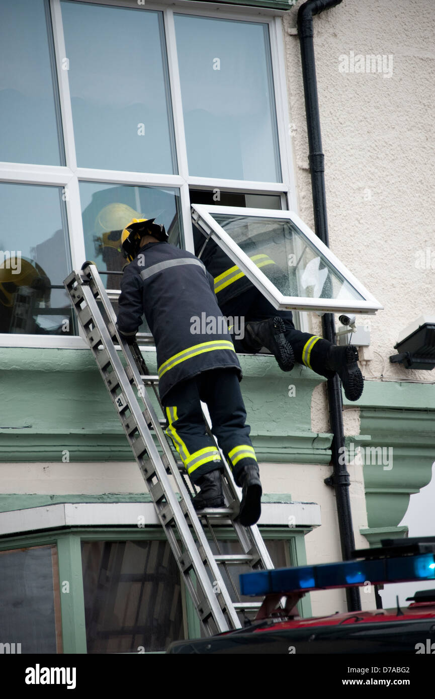 Fireman climbing through window up ladder Stock Photo Alamy