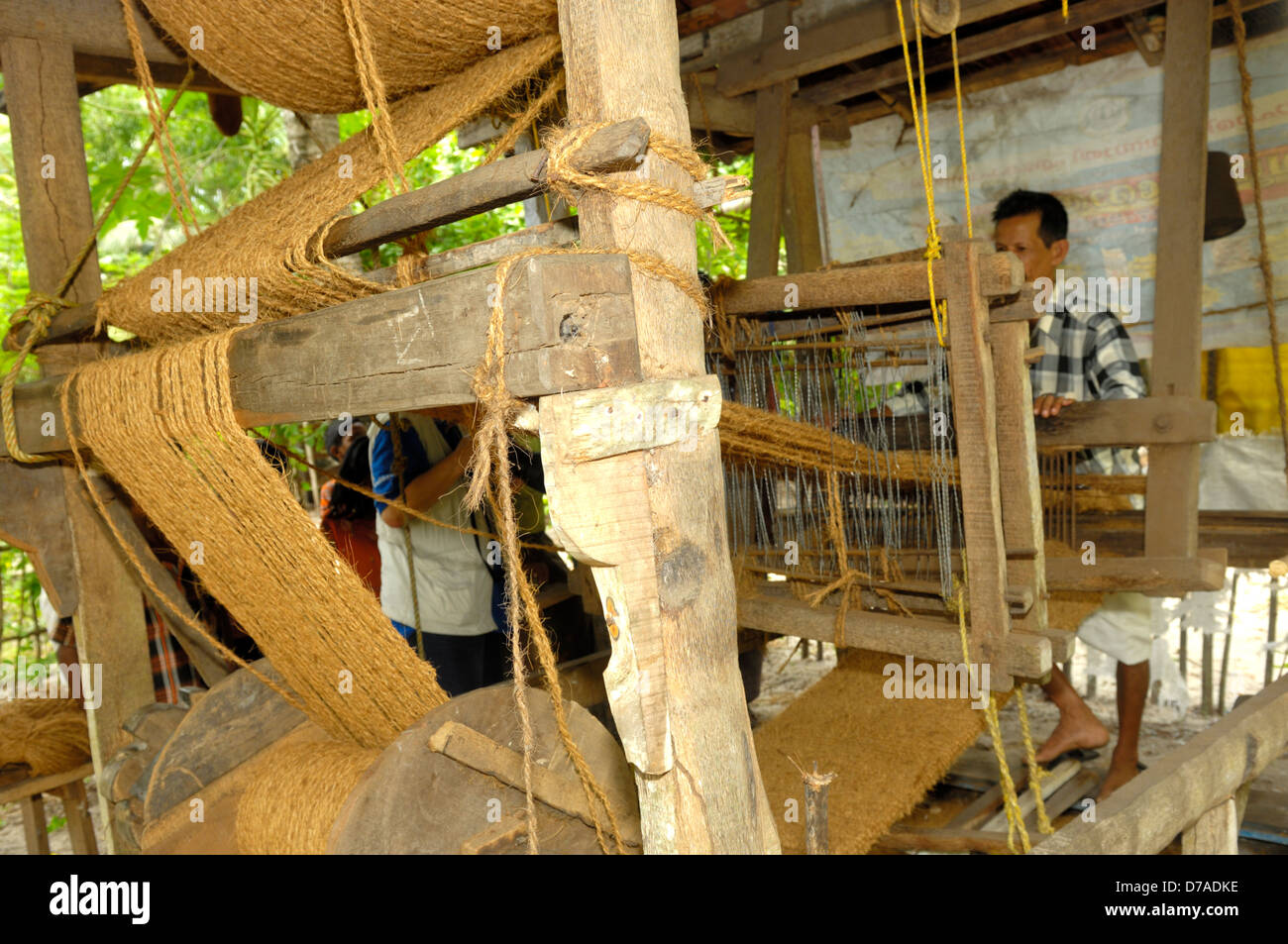 Wooden loom used by man producing coconut fiber coir door mats in home cottage-industry, Kerala, India Stock Photo