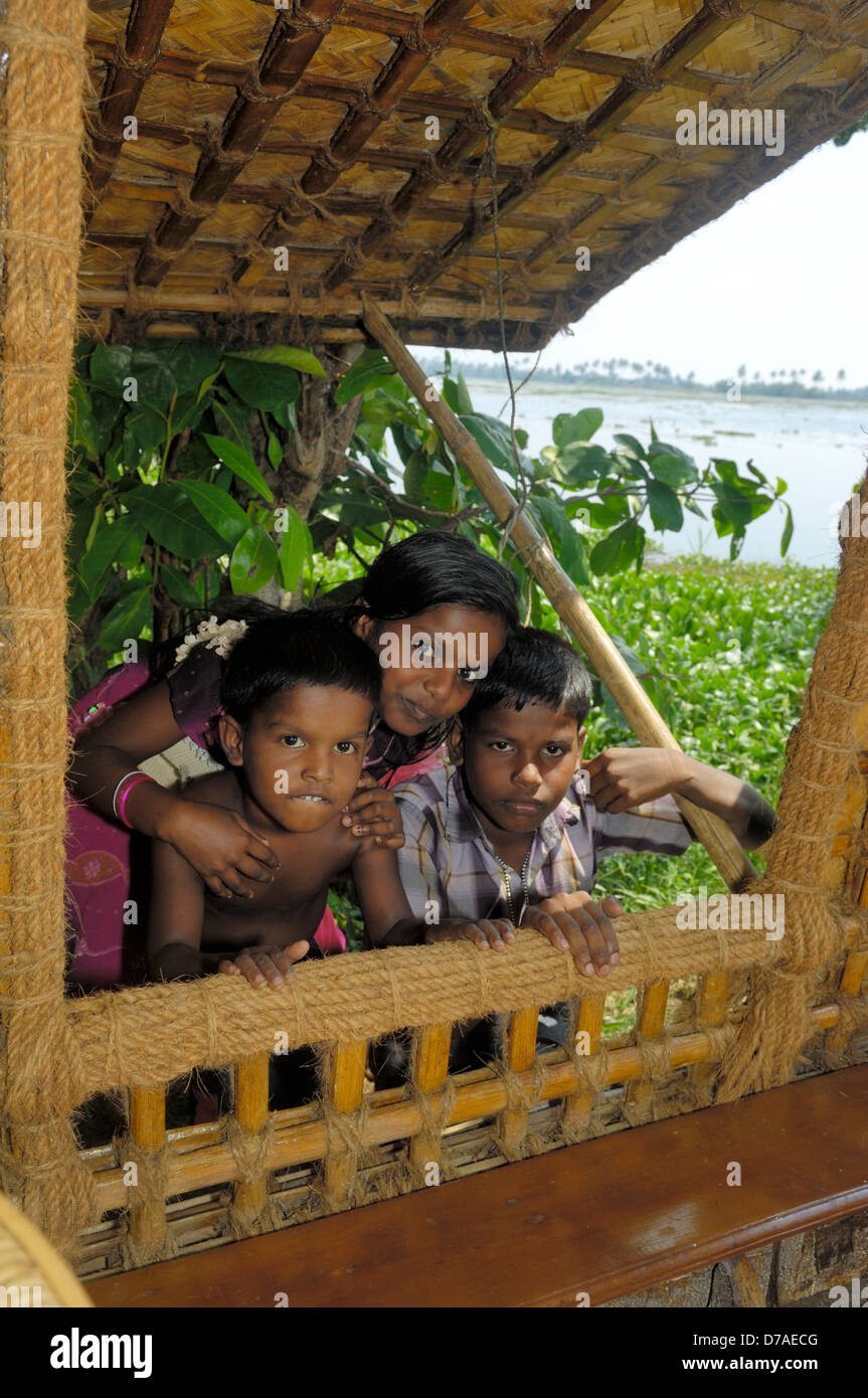 Indian children looking into traditional rice boat in the backwaters of Kerala Vembanad waterway, India Stock Photo