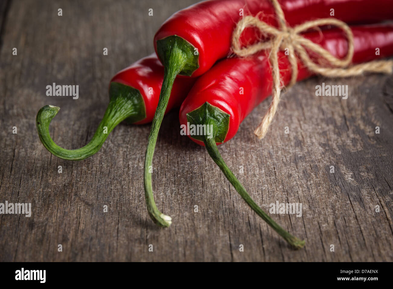 tied red chili peppers on old wooden table, with scratches Stock Photo