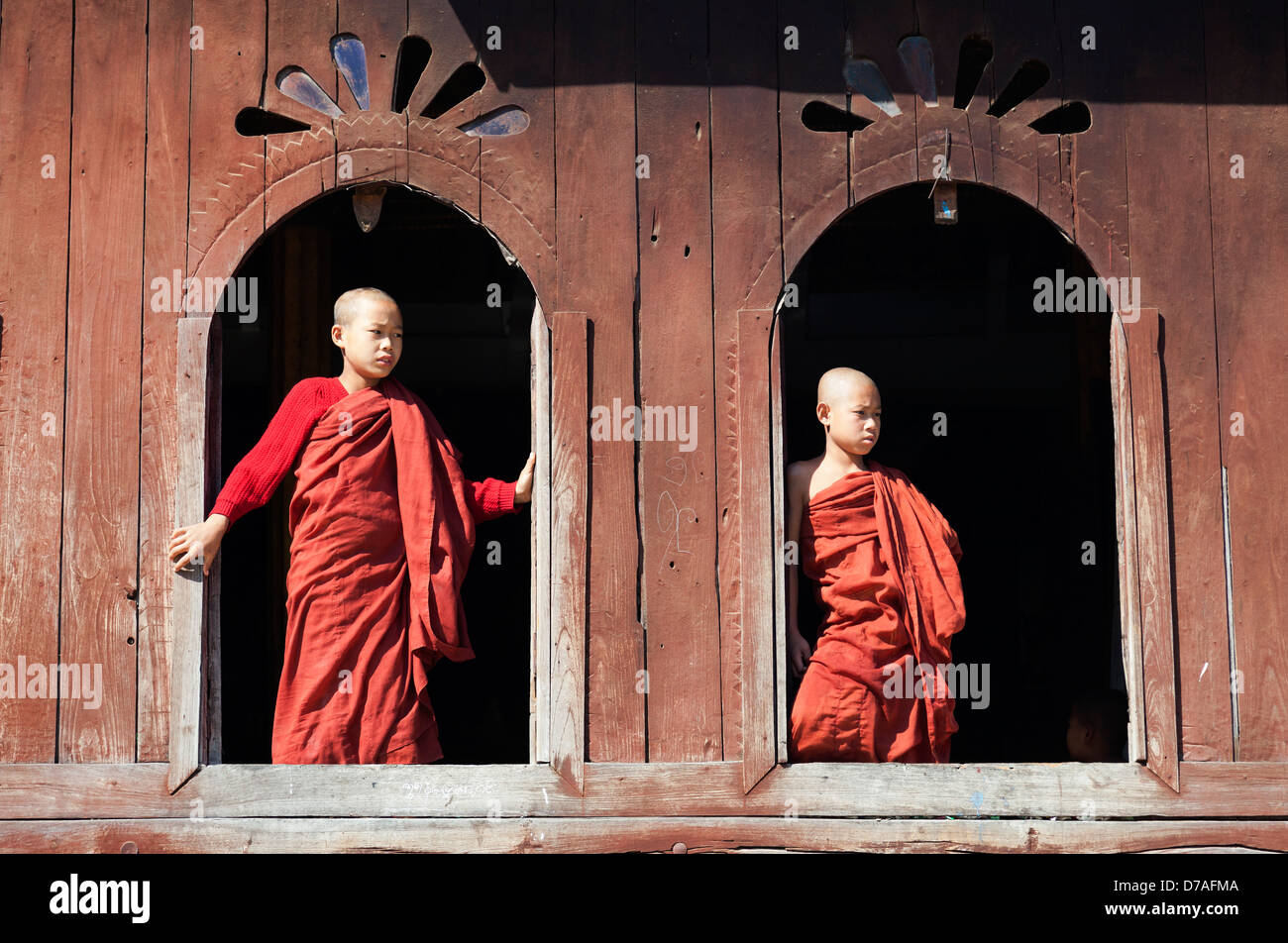 Two young monks by the window in Shwe Yaunghwe Kyaung Monastery near to Lake Inle, Myanmar Stock Photo
