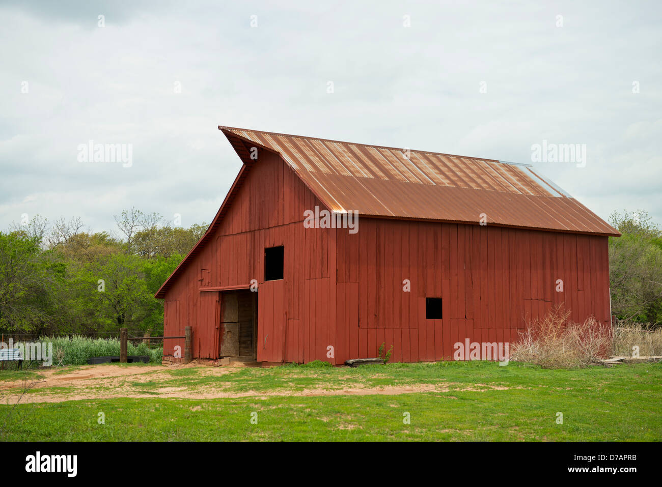 A red barn with a rusty tin roof on a farm in Oklahoma. Stock Photo