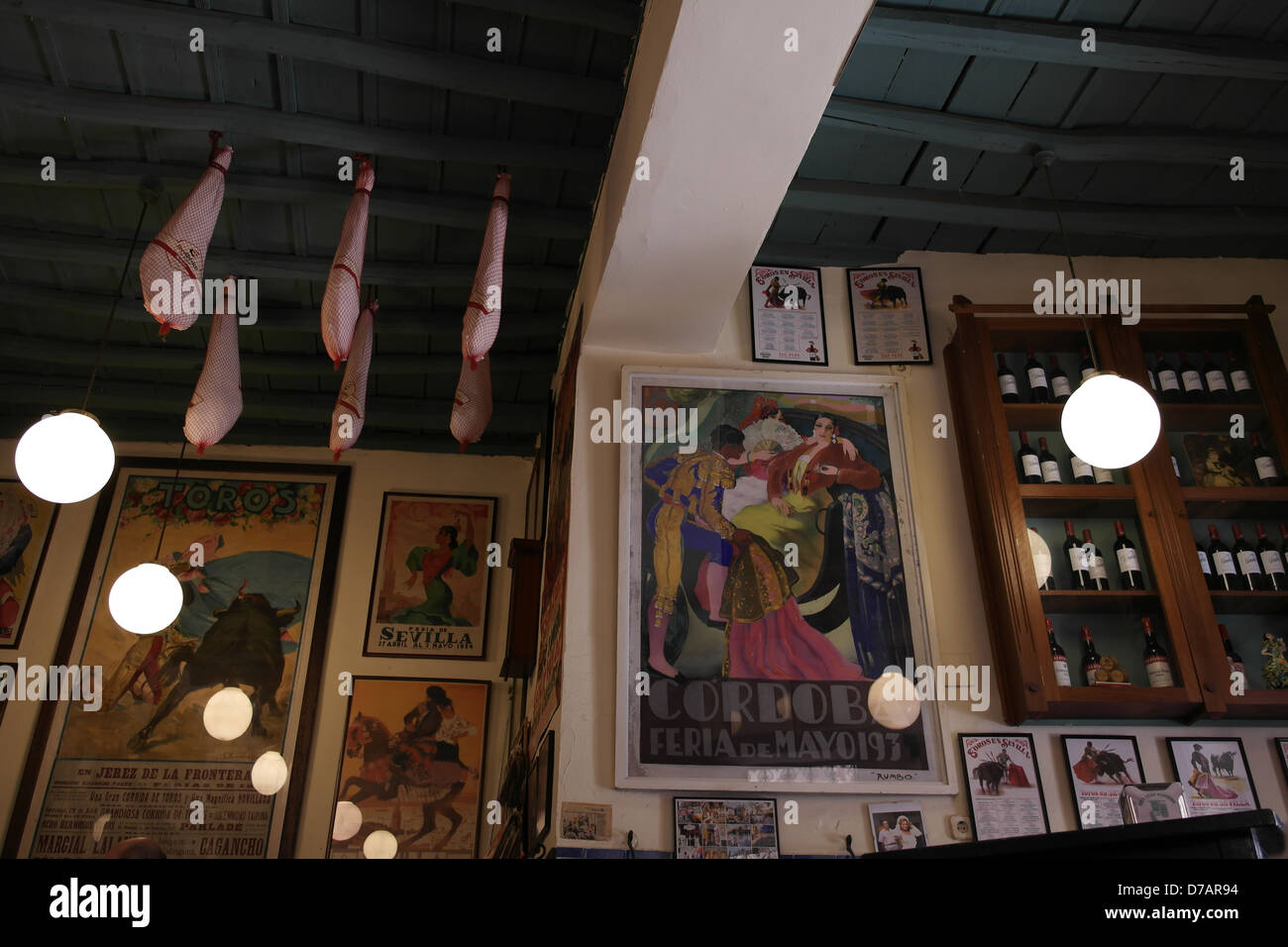 Inside a small traditional bar in the back streets of Seville, with bullfighting posters and iberian ham hanging from rafters Stock Photo