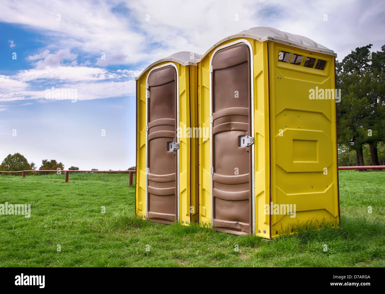Two yellow portable toilets at a park Stock Photo