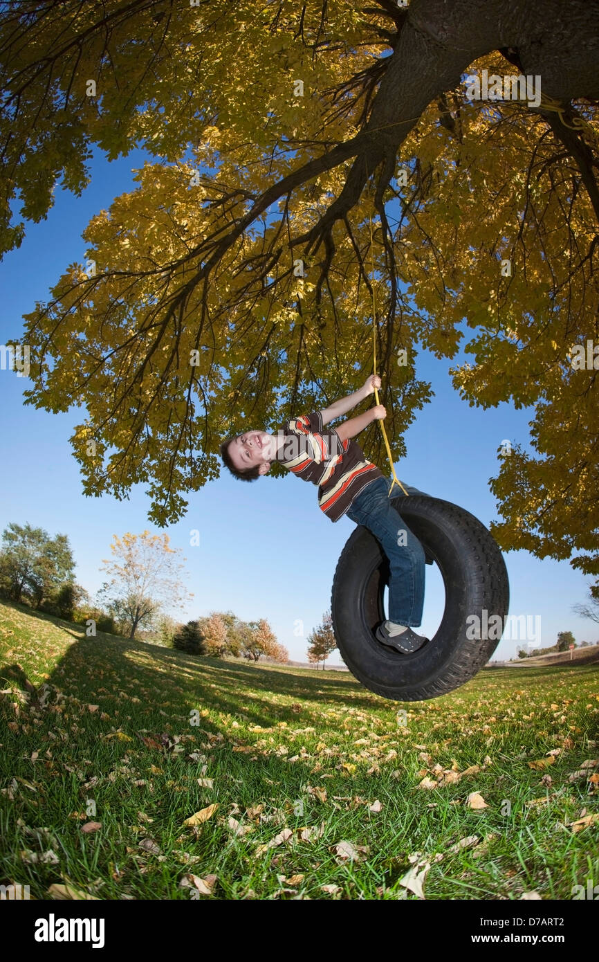 Boy Swinging On A Tire Swing In The Fall Stock Photo - Alamy