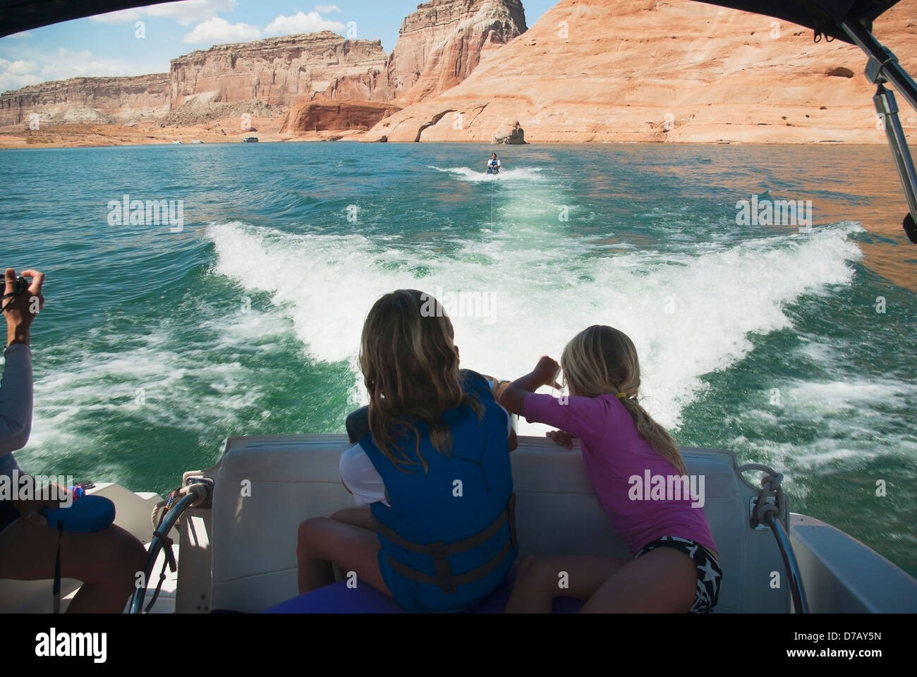 Two blond girls on back of speedboat watch their father on wakeboard behind speedboat on lake powell; page arizona usa Stock Photo