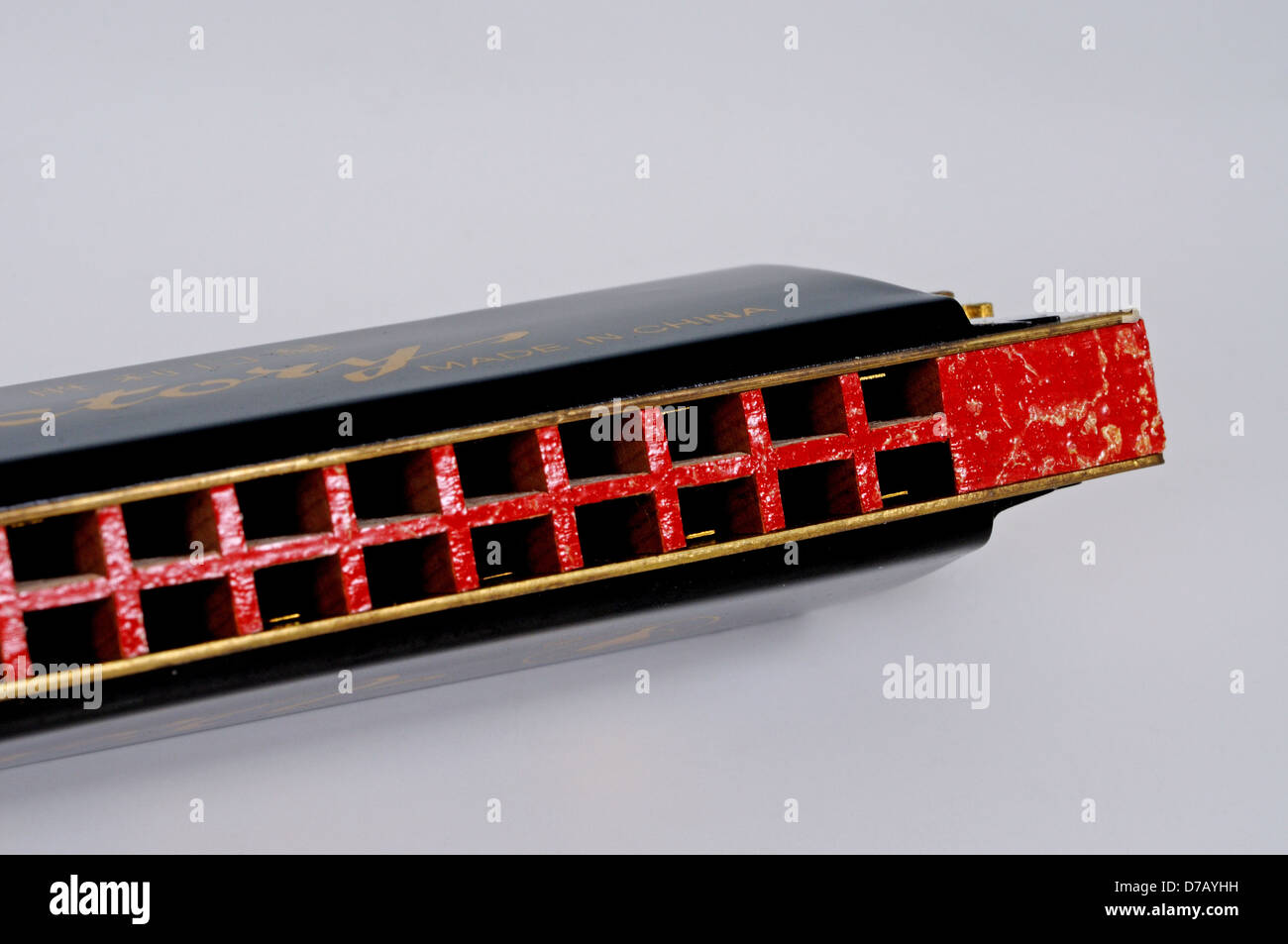 Red and black harmonica against a grey background. Stock Photo