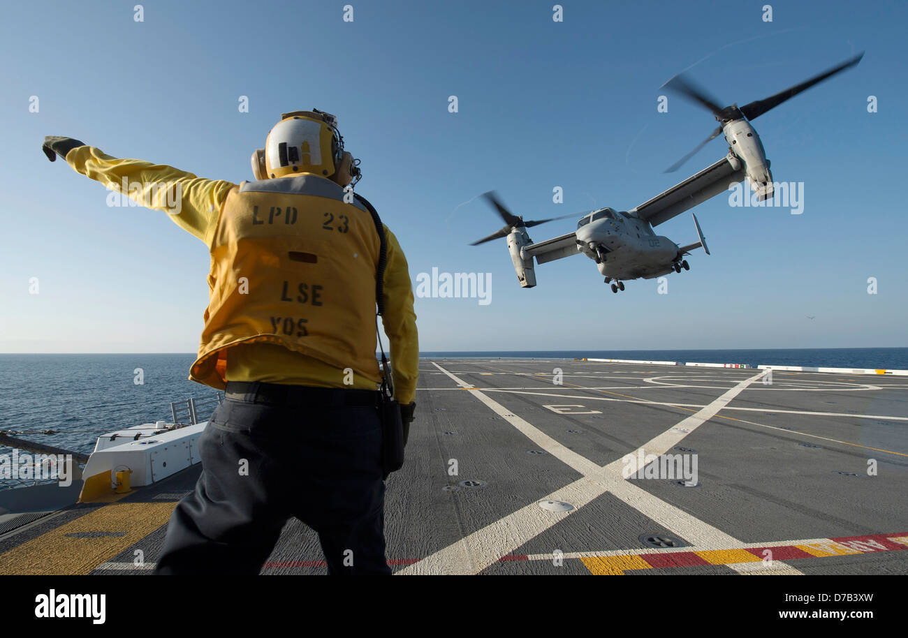 A US Navy Aviation Boatswain's Mate directs the launch of an MV-22 Osprey tilt rotor aircraft on the flight deck of the Amphibious Transport Dock Ship USS Anchorage April 24, 2013 in the Pacific Ocean. Stock Photo