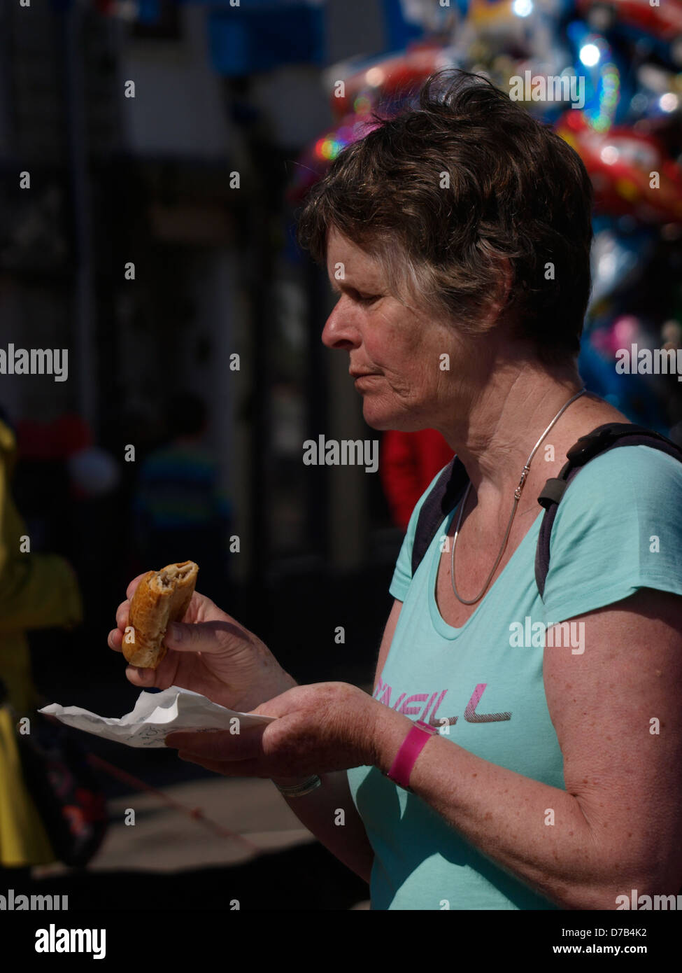 Middle-aged woman eating a sausage roll, UK 2013 Stock Photo
