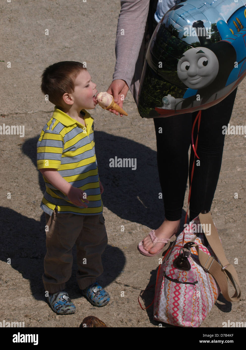 Young boy licking his mother's icecream, UK 2013 Stock Photo