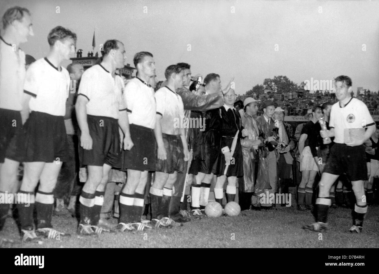 After beating Hungary 3:2 in the 1954 FIFA Word Cup final at Bern's Wankdorf stadium on the 4th of July in 1954, German team captain Fritz Walter (r) is proudly holding the conquered Jules-Rimet-Cup in his hand. In front of him a line-up of the German team for the victory ceremony. The picture shows (l-r) Jupp Posipal, Hans Schäfer, Werner Kohlmeyer, Karl Mai and Max Morlock. Stock Photo