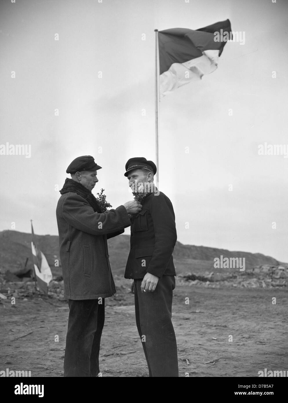 The flowers with which the people of Heligoland are dressed up are a visible sign of their joy; in the background the flag of Heligoland is fluttering. Because on 1 March 1952, the island Heligoland was given back from the British government to Germany after having become a forbidden, dead zone and bomb training area of the British air force after a bombardment during the Second World War and an enormous explosion. Stock Photo
