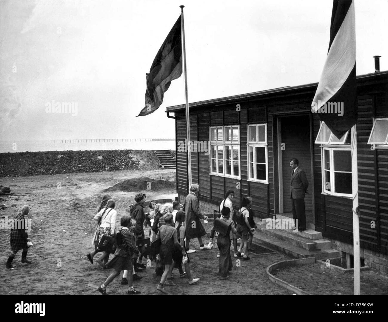 Pupils enter the school building in Helgoland in 1954. On the 18th of August in 1954, the running of the school began.The British try to destroy Helgoland completely on the 18th of April in 1945. After World War II the population was expelled from the island, while Britain occupied the island for seven years and destroyed it by blastings. The island was given back on the 1st of March in 1952 at midnight, which was celebrated with a ceremony. Stock Photo